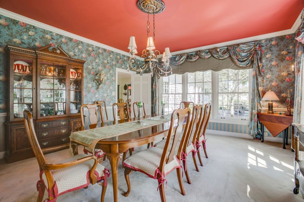 Formal dining room with pink ceiling, Southern-style wallpaper, and ornate furniture.