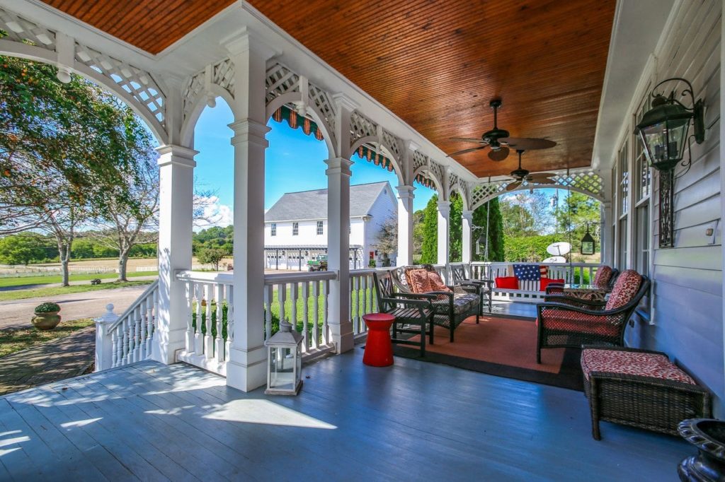 Beautiful covered front porch with white columns and patio furniture.