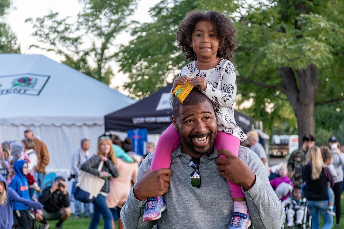 A man carrying his daughter on his shoulders.